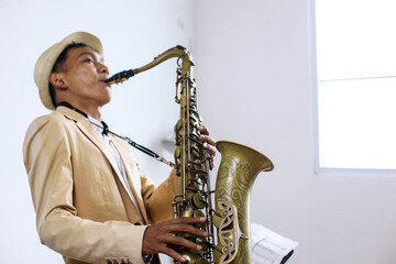 Portrait Of Young Asian Guy Jazz Musician Playing The Saxophone In The Studio
