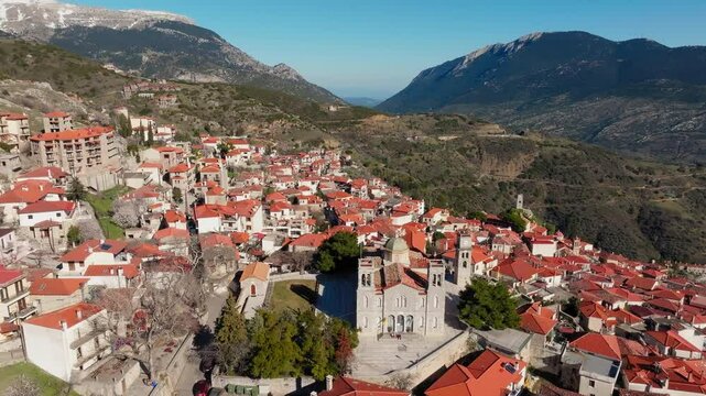 Church of Agios Georgios reveals Arachova mountain town uphill houses, cobbled streets, Viotia, Establishing drone shot