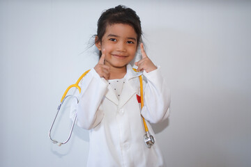 Little asian girl wearing a white coat playing doctor with holding a stethoscope in her hand. Perfect for themes related to education, creative play, and children's health.