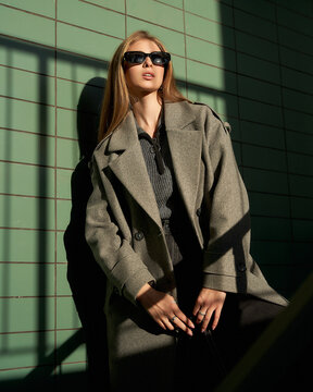 Striking pose by a female model in stylish coat under dramatic lighting