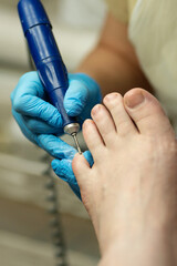 Gloved technician performs dry pedicure with precision on toenails. Chiropody and podology concept,...