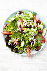 Healthy and tasty salad with feta cheese, various tomatoes, olives, cucumber, onion and lettuce.	