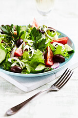 Healthy and tasty salad with feta cheese, various tomatoes, olives, cucumber, onion and lettuce.	