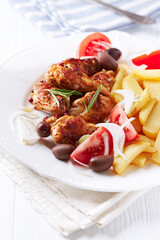 Spicy chicken wings with french fries and tomatoes. Close up.	