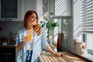 Happy woman enjoying in fresh orange juice in morning at home.