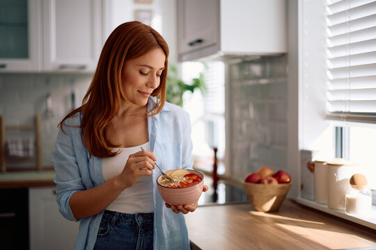 Smiling woman having healthy breakfast in kitchen.