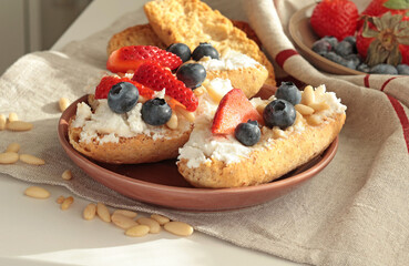 Crostini with ricotta, berries, pine nuts. Slices of toasted bread with cheese for breakfast. A...