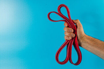 Holding red resistance bands against a blue background
