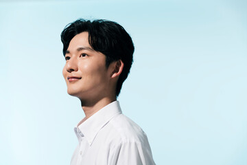 夏の日差しの中にいる白シャツを着た若い日本人男性