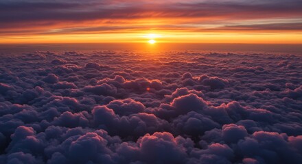 Obraz premium Aerial View of Sunset Over Cloudscape - Stunning aerial shot of a sunset over a vast sea of clouds, bathed in warm orange and purple hues