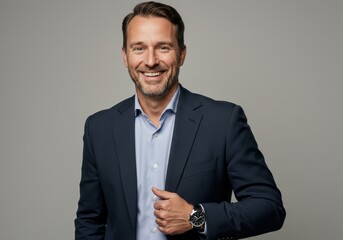 Smiling businessman in a suit poses against a gray backdrop with a confident and approachable demeanor
