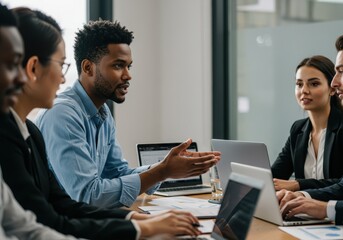 Diverse group of business professionals collaborating around a conference table with laptops in a modern office