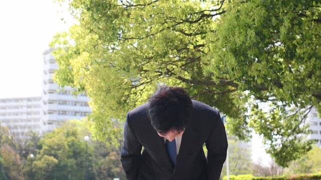 屋外でお辞儀をするスーツ姿のビジネスマン