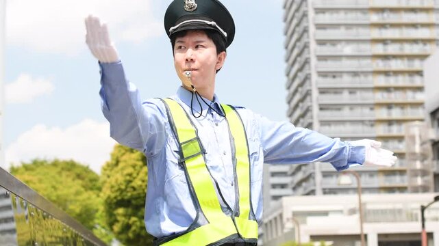 交通誘導をする警備員のアジア人男性
