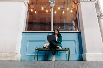 Businesswoman working on a laptop outside a cafe in the city
