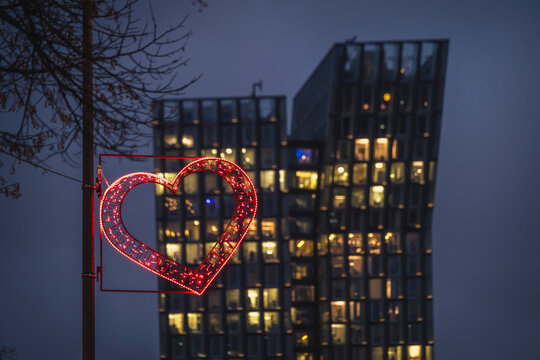 Neon heart light in front of modern buildings at night in Hamburg, St. Pauli