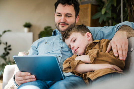 Father and son spending quality time together learning on a tablet indoors