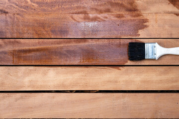 Paint brush apply varnish on new surface of lumber, wood product in top view. Look wet, elegance and darker brown color to improve or coating stain grain surface suit for construction concept.