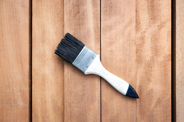 Paint brush place on pile of lumber, wood product in top view. Construction material and tool for improve, protective or coating stain grain surface. Include empty space suit for background.