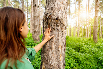 Woman connecting with nature by touching tree trunk in forest