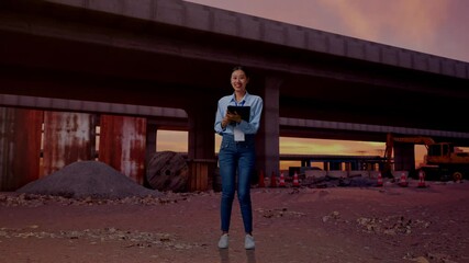 Full Body Of Asian Female At The Site of Highway Construction, Typing On Tablet'S Keyboard And Looking Camera And Smiling