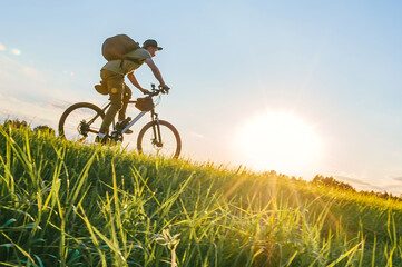 Unrecognizable man riding bicycle in countryside