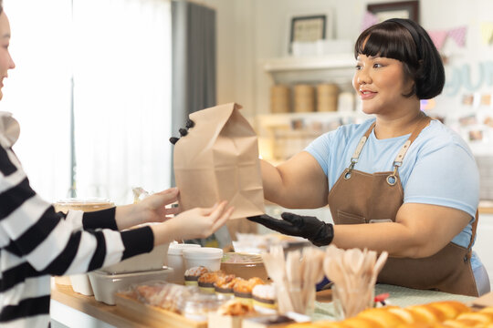 Small business owners are selling .Handsome young caucasian waiter servicing the customer with swiping machine in a cafe. Cashless contactless payment with credit debit card. E-banking .
