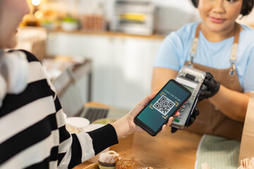 Small business owners are selling .Handsome young caucasian waiter servicing the customer with swiping machine in a cafe. Cashless contactless payment with credit debit card. E-banking .