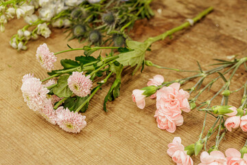 Florist arranging pink carnations and chrysanthemums on wooden table, mothers day