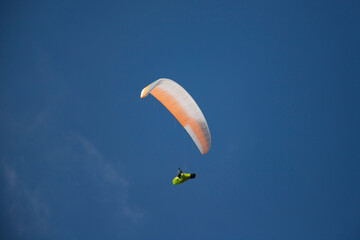 A man with a paraglider in front of a blue sky.