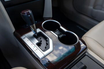Portland, OR, USA - Gear shift console of a 2013 Japanese sedan with leather-trimmed handle, wood finish, gear indicators, and dual cup holders in the center section