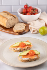 Healthy toast with smoked salmon, avocado and cherry tomato on multigrain bread, served on a beige plate. Concept of healthy breakfast and modern lifestyle