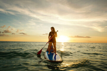 Teenage girl paddle boarding with younger sister Gulf of Mexico