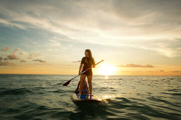 Profile teenage girl paddle boarding at sunset Gulf of Mexico