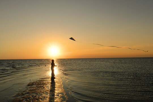 Side view tween girl flying kite on beach sunset Outer Banks