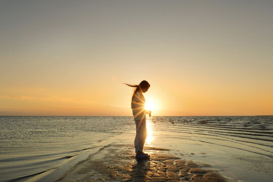 Side view young girl standing on beach sunset Outer Banks