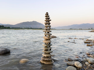 Stacked round stones sculpture artfully balanced in flowing river