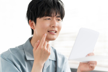 部屋の中で鏡を見ている20代の日本人男性