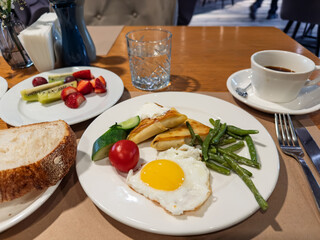Hotel Style Breakfast: Fried Egg, Blini with Sour Cream, Beans, and Fruit Salad.Balanced Morning Meal: Egg, Blini, Green Beans, Fresh Fruit, and Coffee