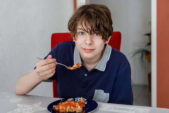 Teenager boy eating tomato bolognese pasta for lunch. Hungry school teenage child having healthy food