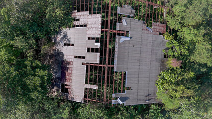 Old abandoned steel framed warehouse in the middle of the forest. Aerial View.