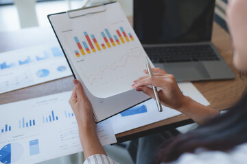 Businesswoman analyzing financial charts and graphs at workplace