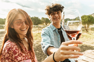 Young friends toasting with red wine in nature, happy outdoor moment