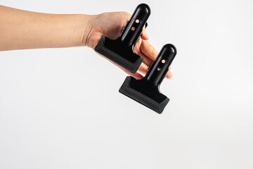Black plastic spring clamp in hand isolated on white background.