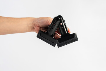 Black plastic spring clamp in hand isolated on white background.
