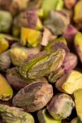green pistachios peeled from the shell, salted crunchy nuts, pistachios without shells, cut into small and large pieces on a board