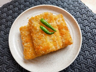 Crispy Golden Fried Risoles with Green Chili Garnish on a White Plate.