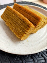 A close-up shot of perfectly sliced of Lapis Legit, a traditional Indonesian layer cake, showcasing its beautiful golden layers and rich texture. This sweet and spiced cake is a beloved delicacy.