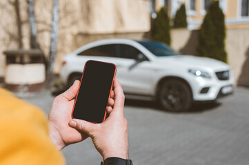 Close-up, Mockup of a smartphone in the hands of a man. Against the backdrop of a white car.