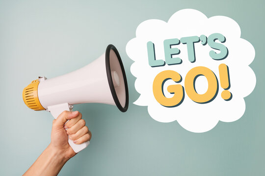 Hand holding megaphone announcing "Let's Go!" in a speech bubble, against a pale-green background, showcasing motivation and announcement concepts
